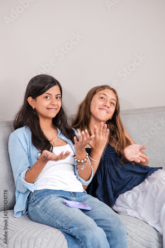 Teenage friends performing the trending six seven hand gesture and talking happily on living room sofa
