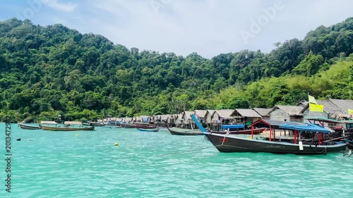 Sea gypsies wooden frishing boat on turquoise water n calm ocean wave at Moken or Morgan Village in Surin island on clear blue sky n white cloud with mountain n rain-forest in Phang-Nga, Thailand
