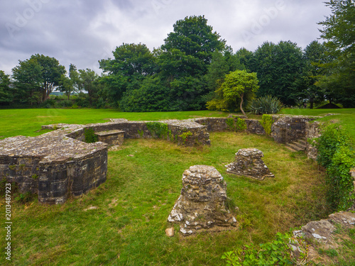 Bild auf Leinwand Medieval stone ruins and column bases of a former abbey crypt surrounded by gree
