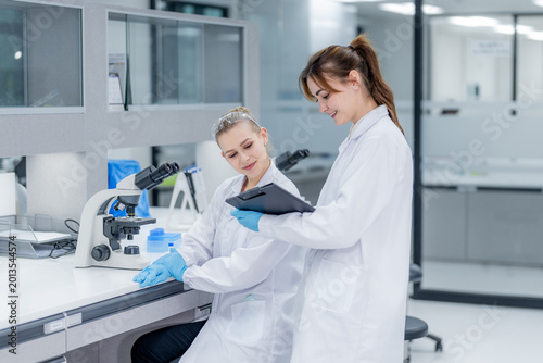 Фотография Two scientists work together in a modern lab discussing results while using a ta