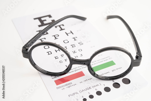 Foto Glasses on eye testing exam chart to check eyesight accuracy of reading