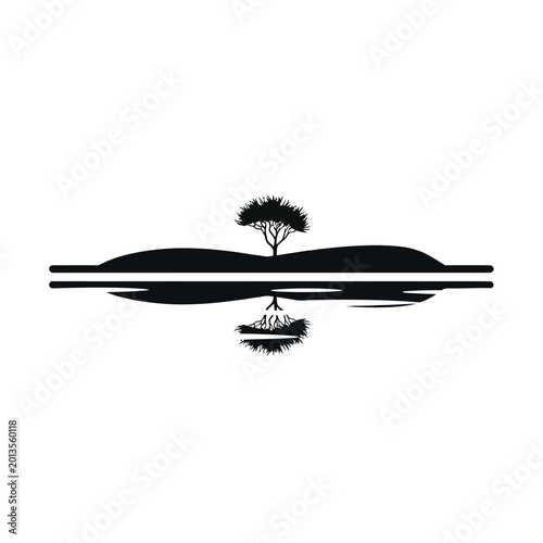 Silhouette of a lone tree on a hill reflected in water.