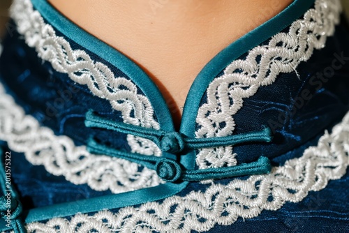 Close-up of traditional garment with intricate lace trim and decorative buttons