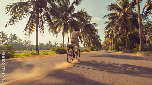 Cycling, tropical road, palm trees, sunny day, motion blur