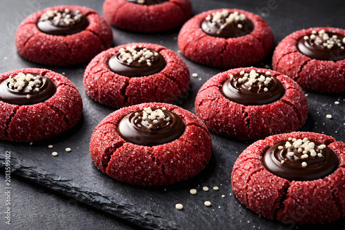 Designer showcases red velvet thumbprint cookies paired with contrasting dark slate surface and soft highlight gradients