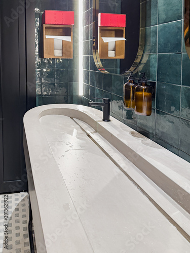 A Modern Bathroom Featuring Sleek Designs with a Curved Concrete Sink, Stylish Accessories, and Elegant Tiling for a Contemporary Ambience