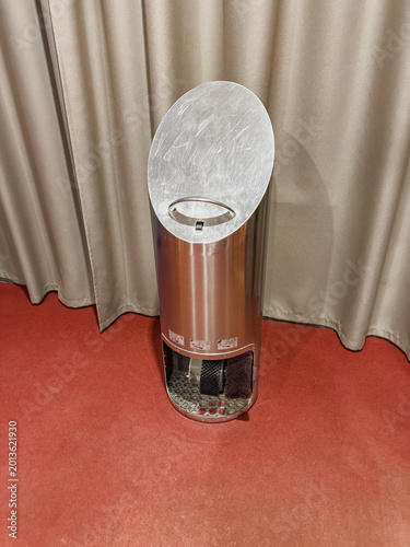 Automatic metal shoe polishing machine stands on red carpet in hotel.