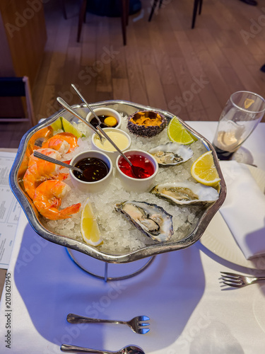 A Lavish Seafood Platter Featuring Fresh Shrimp, Oysters, Sauces, and Lemon Garnishes Served on Ice for an Exquisite Dining Experience