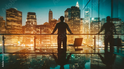 Фотография Confident businessman observing a vibrant city skyline from a high-rise office balcony at night