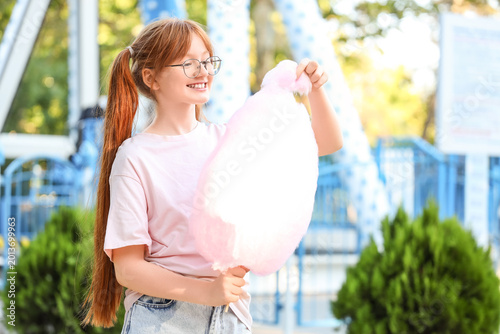 Teen girl eating cotton candy in amusement park