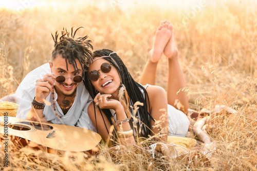 Foto Young couple of hippies with dreadlocks and guitar lying outdoors