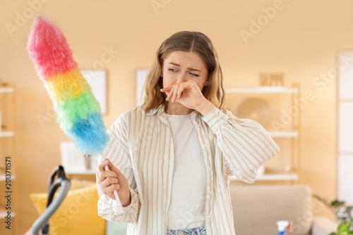 Young woman suffering from dust allergy while cleaning flat