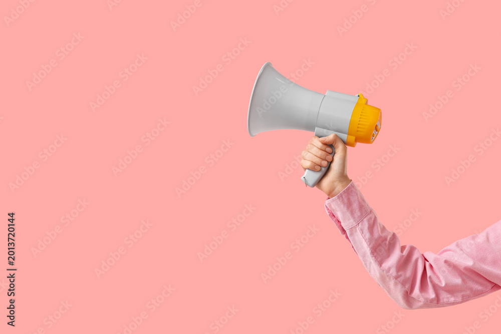 Fototapeta premium Female hand holding megaphone on pink background