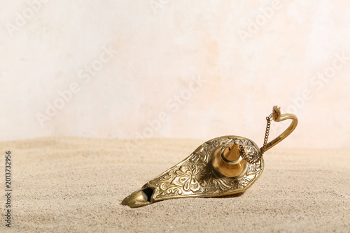 Foto Lamp of Aladdin with sand on light background