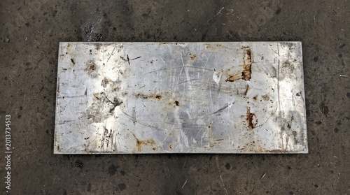 Scratched Industrial Rectangular Metal Plate Surface on Concrete Floor