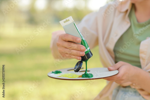Foto Female artist squeezing paint onto palette in park, closeup