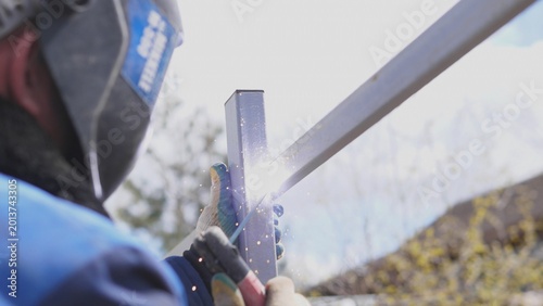 Welder Creating Bright Welding Arc At Joint Outdoors, Intense Blue Light And Molten Pool, Helmet Visor Down, Gloves Gripping Torch, Dramatic Sparks, Safety Oriented Industrial Vibe