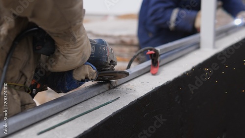 Gloved Hands Tightening Bolt On Metal Beam, Construction Technician Securing Exterior Panel With Clamp And Wrench, Closeup Of Protective Gloves And Tool Interaction, Industrial Rooftop Site,