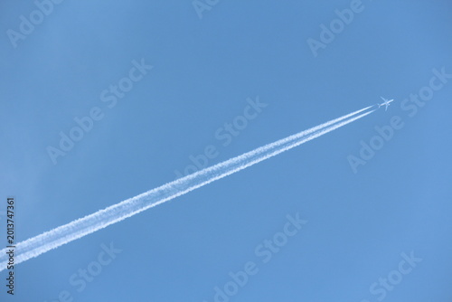 Billede på lærred Jet airplane flying overhead in clear blue sky diagonally with condensation trai