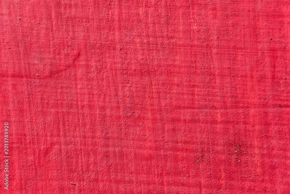 Fototapeta premium Textured red painted wall surface with rough matte industrial finish.