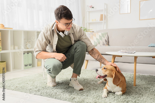 Young man in headphones with cute Beagle dog at home