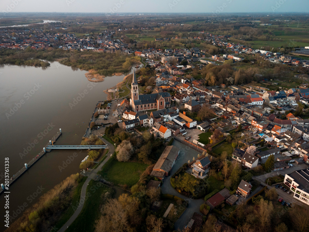 Αυτοκόλλητο Aerial View of a Flemish Town: Historic Church and Residential Areas by the Rive