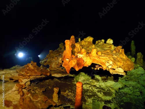 Limestone underwater shapes, cave scuba diving in the cenote. Dark tunnel, lights, scuba diver photographer and colorful stones. Cave underwater photography.