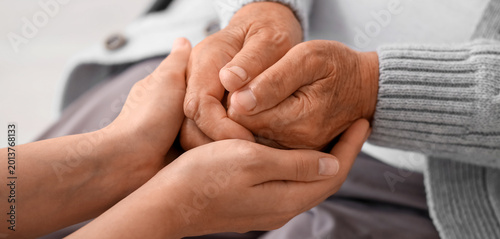Tableau sur toile Young woman with grandmother holding hands indoors, closeup