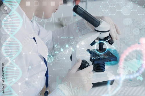 Female scientist looking through microscope in laboratory. DNA research techn...