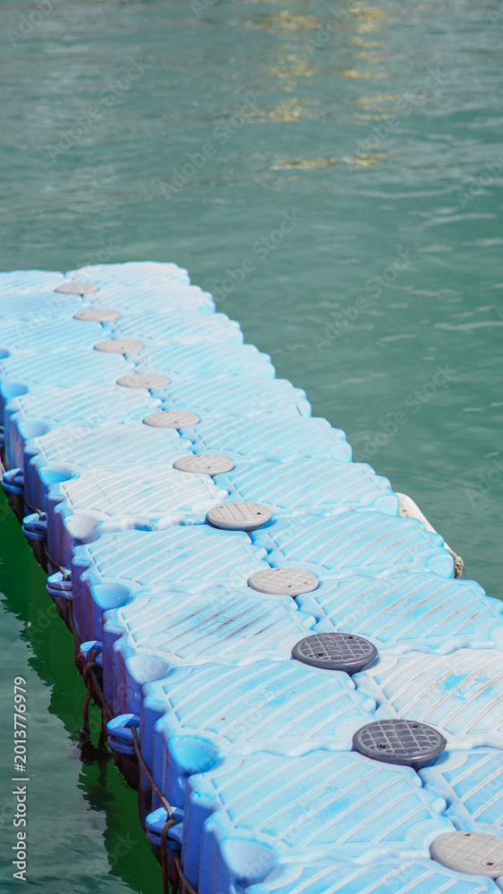 Fototapeta premium A long floating blue plastic modular dock stretching out into the sea.