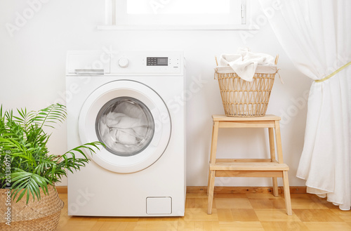 Laundry room interior with dirty clothes in wicker basket near washing machine