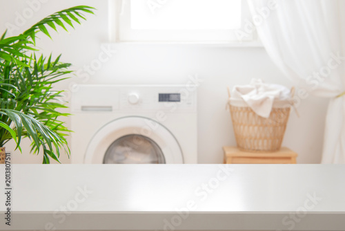 White blank table for design and montage on blurred laundry room background