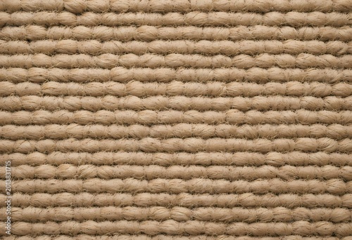 A realistic woven sisal rope mat texture background with coarse fibers and warm natural tan tone