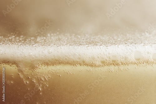 Close-up of foamy beer surface with bubbles and light reflections