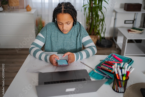 Fotografi Student distracted by smartphone while doing homework
