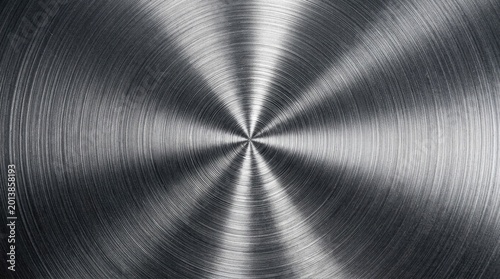 Close-up view of a brushed circular metallic surface with radial patterns and reflections
