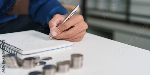 Schilderij op canvas Asian man writing in notebook, planning savings and personal finance