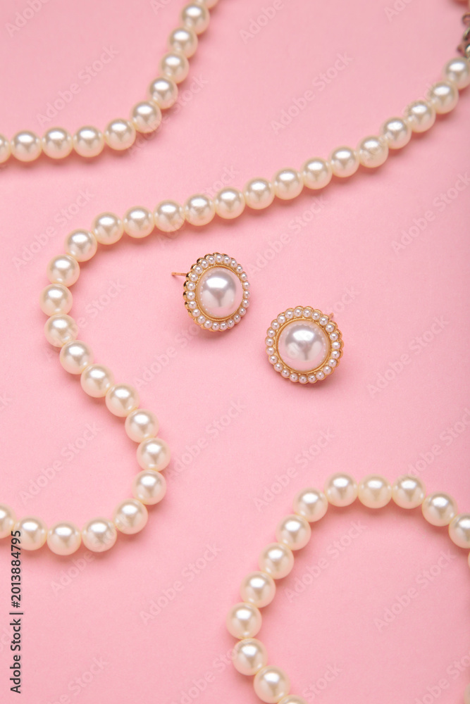 Obraz premium Beautiful pearl earring and necklace on pink background. Vertical photo