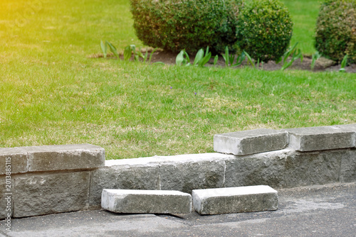 Bild auf Leinwand Damaged low retaining wall with fallen bricks, need for masonry repair in urban landscaping