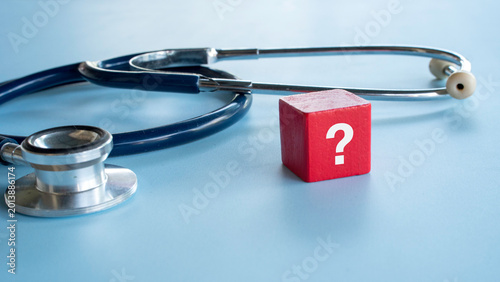Photos A red block with a white question mark standing next to a medical stethoscope on