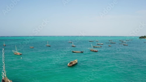 Aerial top view of traditional fishing boats in the turquoise water of Kiwengwa beach, Zanzibar. Tropical landscape with white sand and clear Indian Ocean in Tanzania. Drone 4K