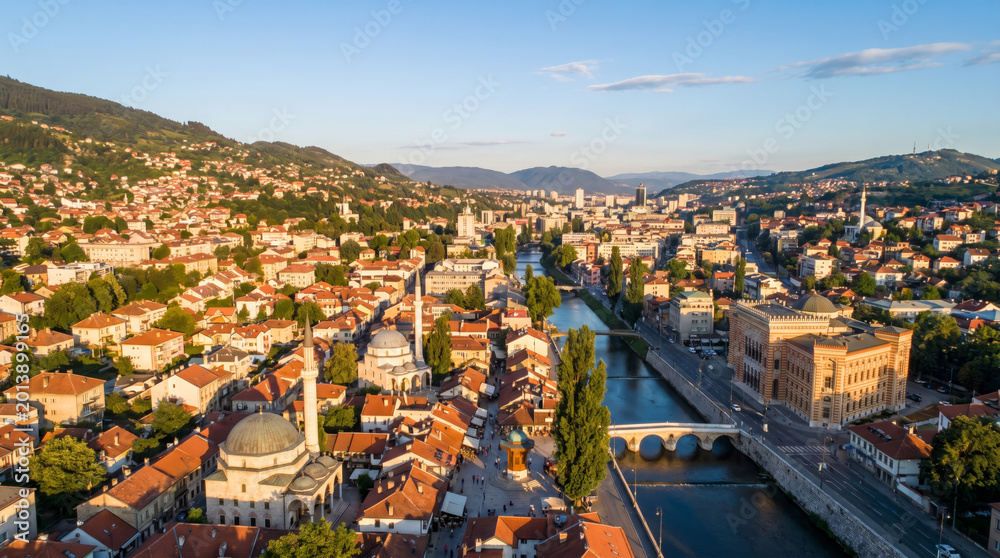 Obraz premium Aerial view of Sarajevo's historic old town with mosques and a river at sunset.