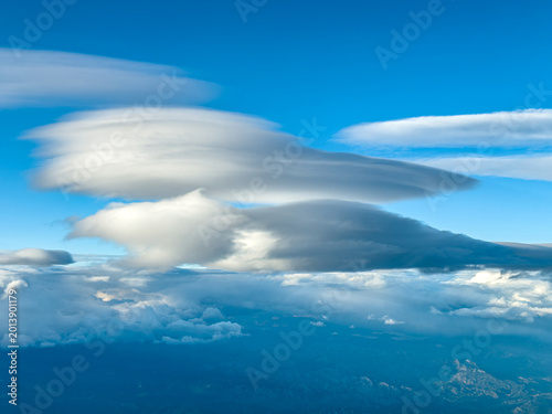 Expansive aerial landscape with dramatic lenticular cloud above distant mountains and valleys
