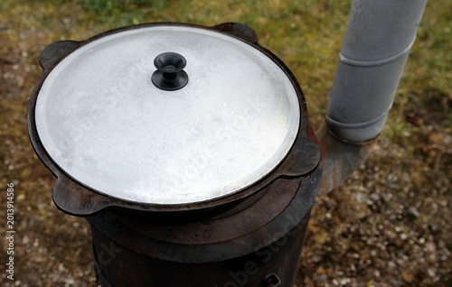 Tableau sur toile Cast iron kazan with lid on a traditional wood-burning stove outdoors