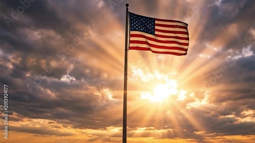 American flag waving on tall flagpole against dramatic sunset sky with radiant sunbeams, camera rising upward from man standing below in powerful patriotic cinematic scene.
