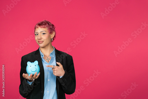 Young person holding blue piggy bank pointing at it