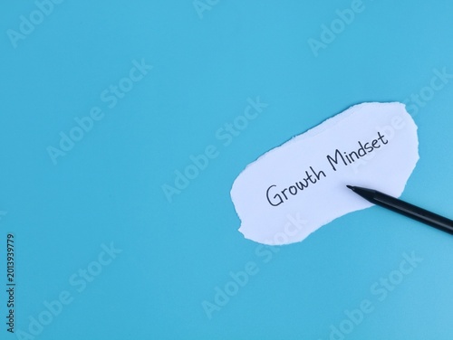Handwritten growth mindset text on torn paper with pen on blue background. Symbolizing personal development, education, and psychological resilience