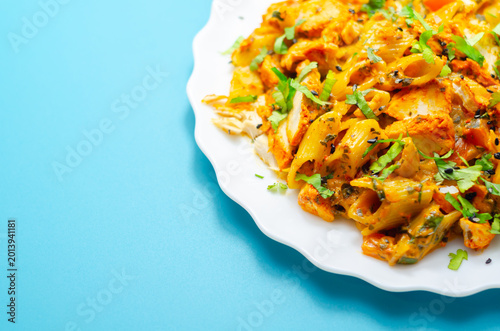 Schilderij op canvas Bright orange pasta dish with chicken and herbs on white plate