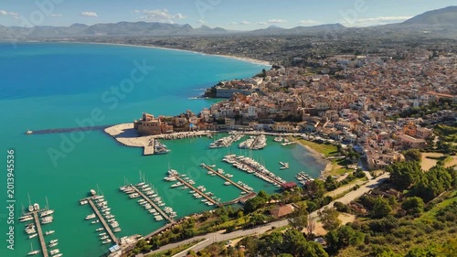 Aerial UHD view of ancient fortress on coast of Castellammare del Golfo, Sicily, Italy. Moored boats fill harbor of Castellammare del Golfo, Italy. Turquoise sea washes Castellammare del Golfo