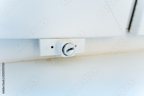 Secure Window Latch. Installation Of Durable Safety Lock On Window With Plastic Mechanism. Fitting Security Latch To White Window Frame Emphasizing Safety And Robust Construction